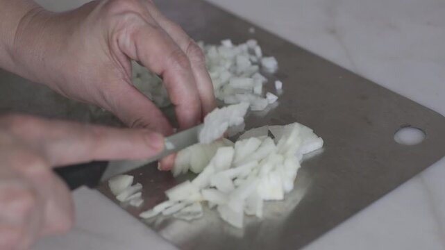 Chopping Onions with a Knife on a Metal Cutting Board