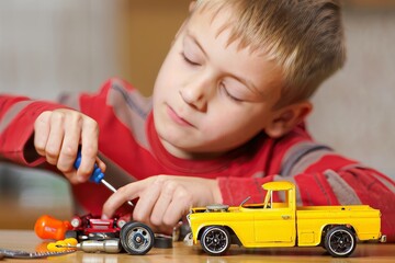 Focused Boy Assembling Toy Car with Screwdriver