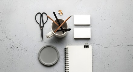 Elevated workspace flat lay featuring essential stationery items like notebooks, pencils, and scissors on a speckled gray backdrop for a modern, minimalist aesthetic.