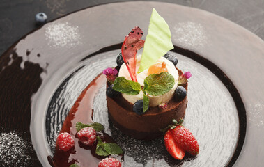 Exquisite restaurant mousse dessert. Chocolate and vanilla souffle on walnut biscuit served on glass plate finely decorated with fresh berries and mint. Exclusive meals and haute cuisine concept