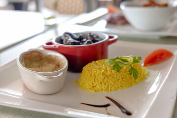 Elegant gourmet dish featuring sautéed veal kidney, yellow rice, and christophine gratin, served with sauce decoration in a fine dining restaurant setting.