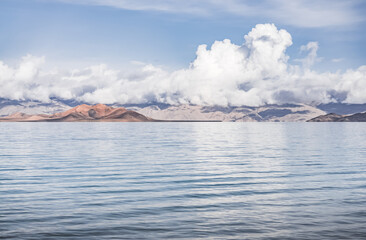Panorama landscape of Lake Karakul in the Pamir mountains in the Tien Shan against the background of high snowy rocky peaks with clouds, morning panorama of the lake for the background