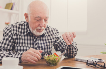 Senior man eating fresh salad side view. Mature male having healthy snack, healthcare, diet concept