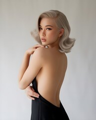 Obraz premium Elegant woman with retro hairstyle wearing black dress looking over shoulder in studio setting