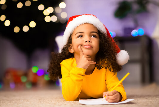 What to ask. Wistful little afro girl thinking about letter to Santa Claus, free space