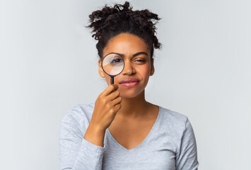 Suspicious young afro woman looking at camera through magnifier, mental disorder illness