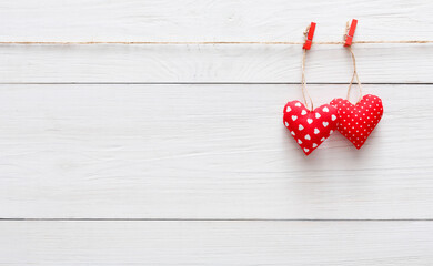 Valentine background with sewed pillow hearts couple on red clothespins at rustic white wood...