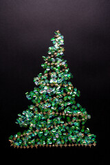 Christmas tree with garland made of green confetti on black background. New year concept with tinsel. Flat lay, top view
