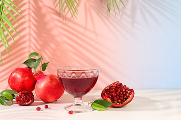 Red pomegranate wine and grains with ripe pomegranates on a trendy table with palm shades, concept festive party, advertising for a bar and cafe. Source of vitamins for a healthy lifestyle,