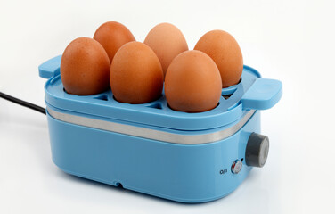 Blue egg cooker steaming six brown eggs on white background