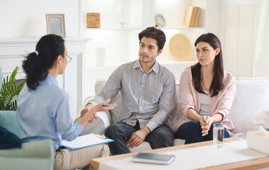 In the therapist's office, a young couple opens up about their relationship, facilitated by a compassionate female counselor aiming to strengthen their bond.