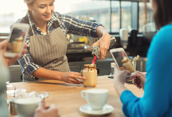 Experienced barista in uniform showing how to make coffee, giving a master class and students taking photos on smartphone. Experience sharing, occupation people and service concept, copy space
