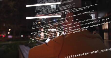 Scanning developer wearing jacket, eyeglasses, using smartphone code overlay on park bench at night
