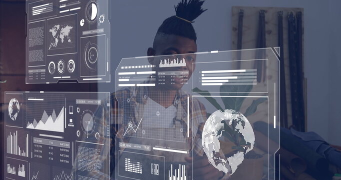 Manipulating charts at office desk, man in plaid shirt, top knot reviewing holographic data panels