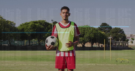 Soccer player wearing fluorescent bib holding black-and-white ball on training field, with goal net