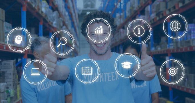 Giving thumbs up, volunteer in blue shirt posing in warehouse, with metal racks and digital icons - Powered by Adobe