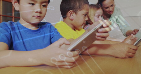 Guiding teacher assisting children using tablets at wooden table in classroom with circuit graphics