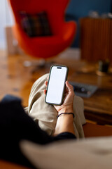 Woman relaxing on sofa holding smartphone with blank screen