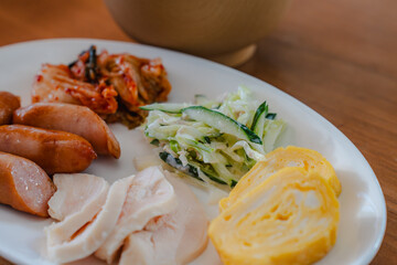Japanese breakfast plate with sausage, chicken ham, omelet, salad, and soup
