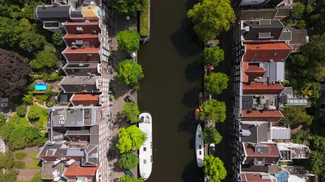 Stunning overhead aerial view beautifully showcases the picturesque canals of Amsterdam, the vibrant greenery surrounding them, and the iconic, charming canal houses that define the city