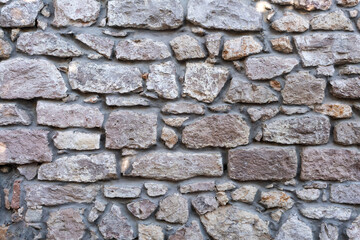 Old textured stone wall with rough surface and natural cement joints, historical architecture background for restoration or construction themes