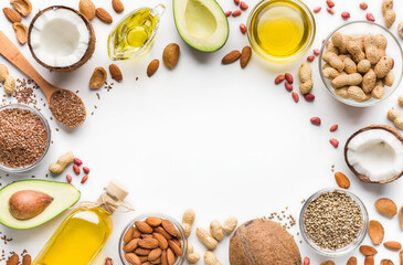 Avocado, coconut, almonds, hemp seeds, linseeds, olives and oils over white background, top view. Alternative oils concept, copy space