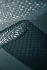 Close up of bubble wrap casting geometric shadows on a surface. Abstract minimal texture in monochrome light.