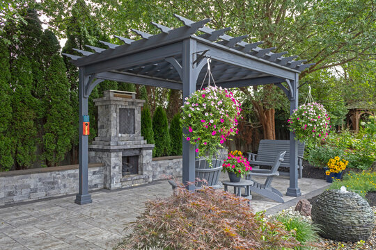 Wooden gray pergola on pavers with stone fireplace and waterfall urns landscape design idea for backyard sanctuary