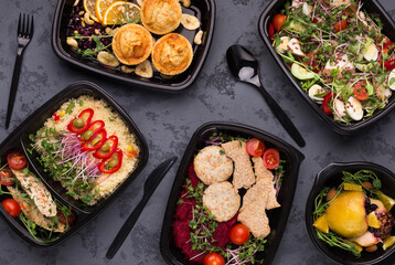 Healthy eating is delicious. Set of various healthy meals in black delivery containers with plastic cutlery, top view