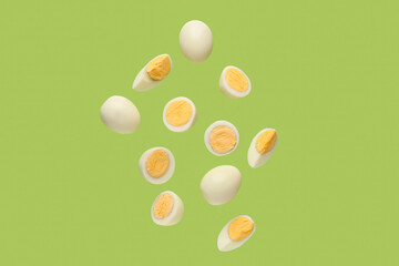Flying boiled chicken eggs on green background