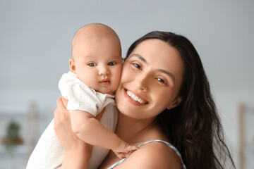 Beautiful young happy mother with her cute little baby at home