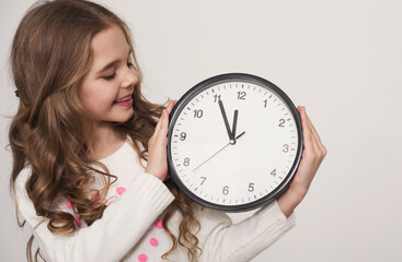 Learning to tell time. Cute little girl holding big clock on white background, copy space