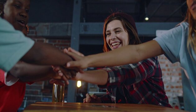 Diverse group of friends joining hands in a casual cafe setting