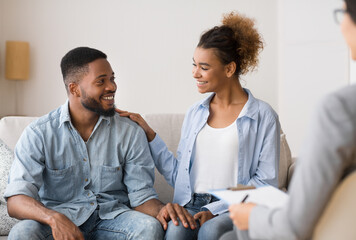 Obraz premium Gladful Black Couple Sitting At Marital Counselor's Office After Happy Marriage Reconciling. Selective Focus