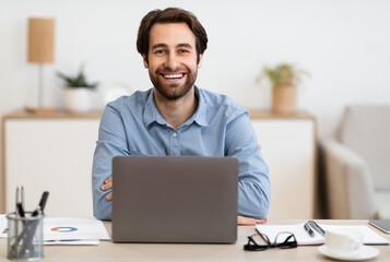 Successful Businessman's Portrait. Happy Entrepreneur At Laptop Computer Smiling To Camera Sitting At Workplace In Modern Office. Freelance Career, Distance Work And Entrepreneurship Concept