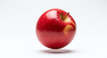 A single shiny red apple with a stem against a plain white background in a studio setting