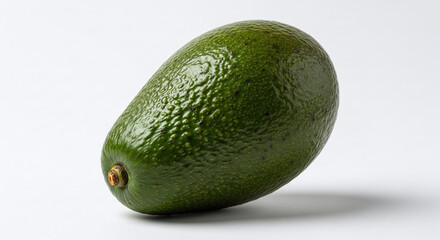 A single ripe avocado with rough green skin resting on a plain white surface in a studio setting