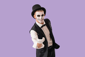 Young happy man dressed as magician skeleton for Halloween on purple background
