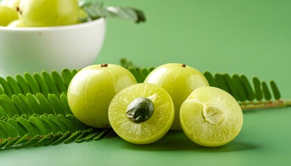 Close-up of fresh, vibrant green gooseberries, whole and halved, with leaves on a bright green background