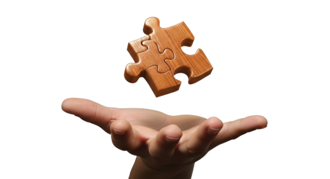 A light brown wooden jigsaw puzzle piece is held aloft by a hand against a plain white background.