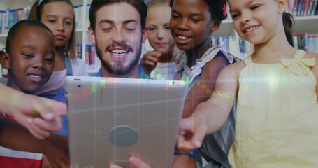 Guiding male tutor showing children data overlay on tablet at library table, with colorful shelves