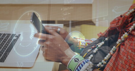 Man in red cloth and bracelets holding smartphone at wooden desk, with laptop and digital overlay