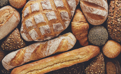 Bread background, top view of white, black and rye loaves on black