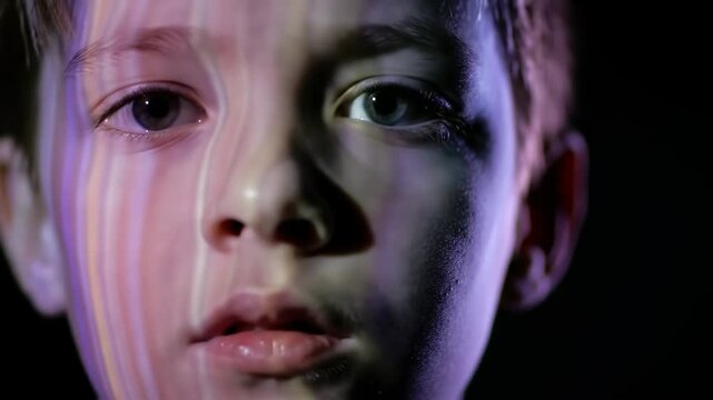 Close-up portrait of a boy with vibrant, colored light effects on his face