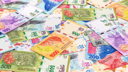 A scattered background of Argentinian peso banknotes in various denominations