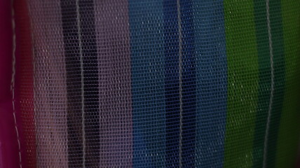 Vertical mesh ribbons in vibrant multicolor array, close-up textile texture with grid like weave and dynamic chromatic contrast
