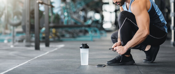 Sportsman tying shoelaces, ready for workout in gym, free space