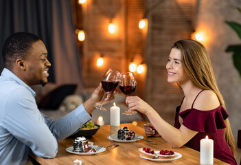 Toast For Love. Romantic Multiethnic Couple Clinking Glasses With Wine On Date In Restaurant, Affectionate Interracial Lovers Celebrating Anniversary Or Valentine's Day Together, Free Space