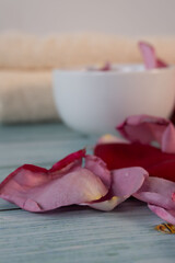 Close-up of flower petals on a table, a bowl and spa towels in the background