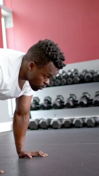 Vertical video: African American man alternating knee drives from plank on mat for core, copy space